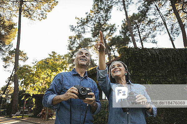 Curious mature couple with camera and binoculars outdoors
