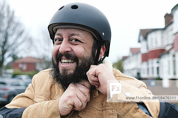 Happy mature man adjusting helmet