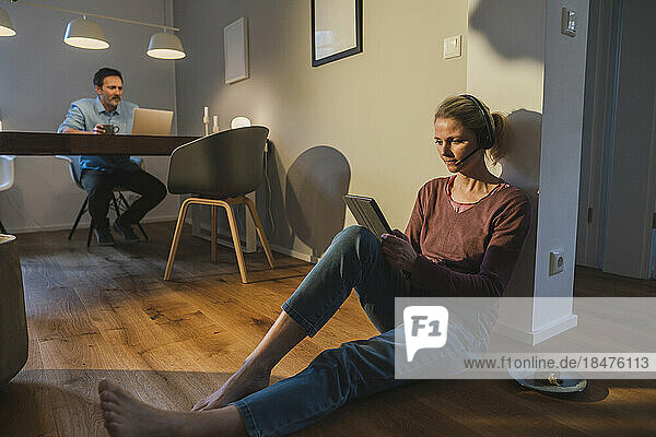 Freelancer working through tablet PC sitting on floor at home