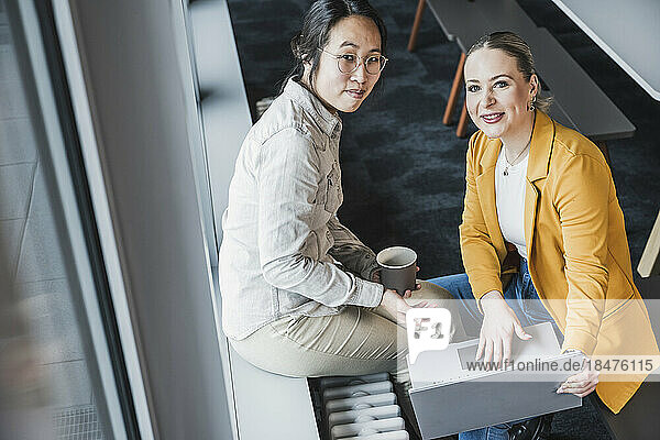 Smiling businesswomen sitting near window at office