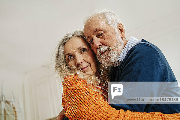 Senior man and woman hugging each other at home