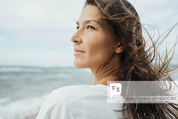 Contemplative woman with long hair at beach