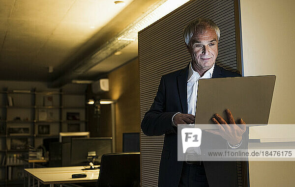 Senior businessman working late on laptop at office