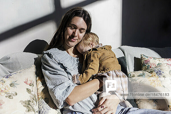 Mutter mit kleinem Mädchen entspannt sich zu Hause auf dem Sofa