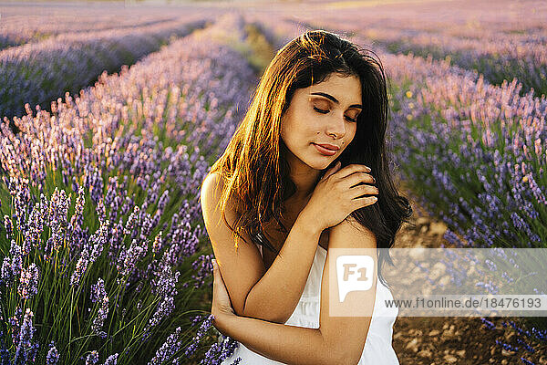 Young woman hugging self in lavender field