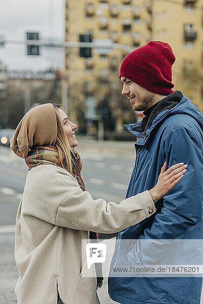 Lächelnde junge Frau berührt Mann  der auf der Straße steht