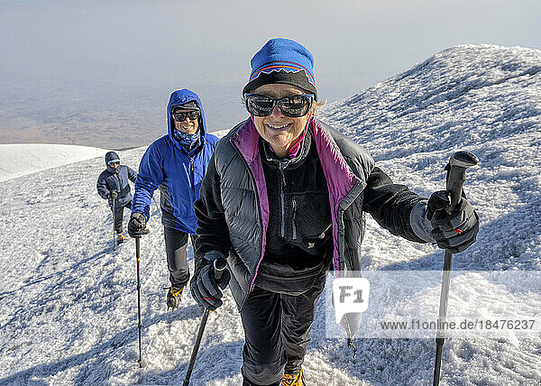 Smiling hikers trekking on snowcapped mountain at weekend
