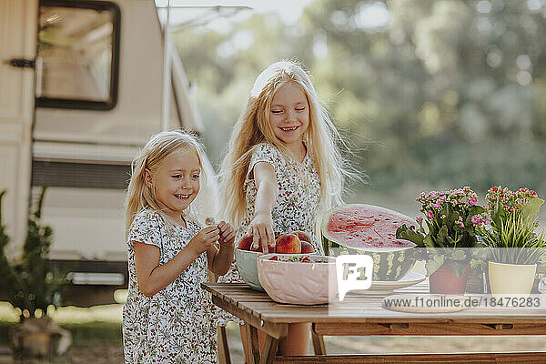 Cute girls eating fresh fruits from table