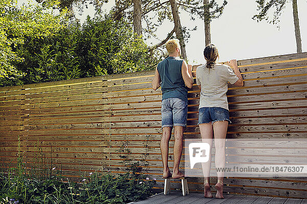 Junges Paar blickt über den Holzzaun im Hinterhof