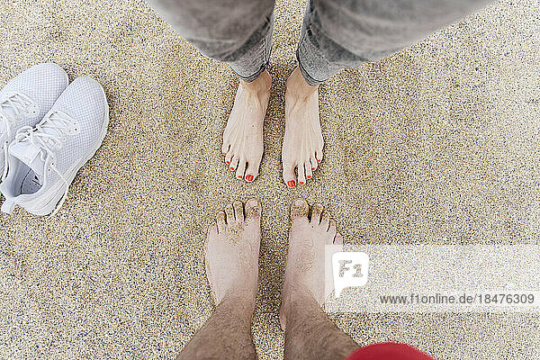 Mann und Frau stehen barfuß im Sand am Strand