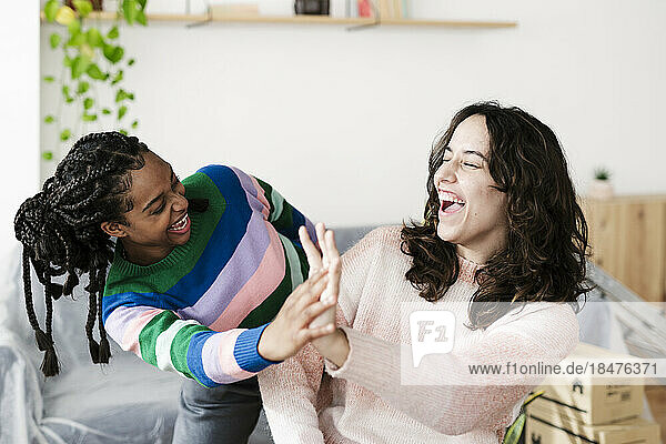 Happy young woman giving high five to friend at home