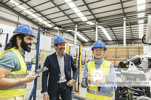Happy businessman with engineers working in factory