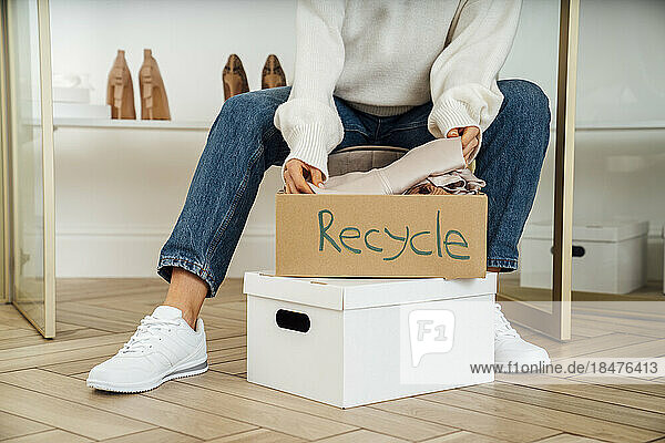 Young woman packing boxes of recycling clothes at home
