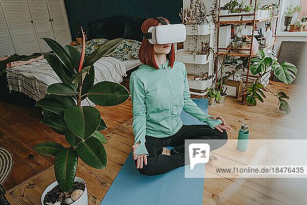 Woman wearing virtual reality simulator doing yoga at home