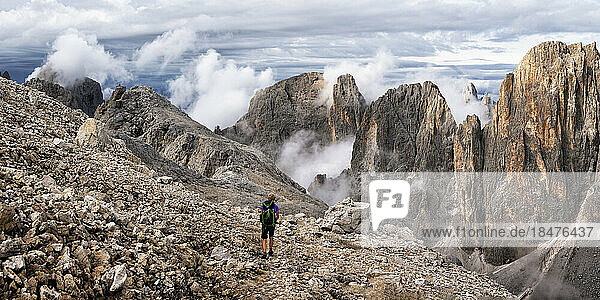 Senior woman hiking on mountain under cloudy sky at Pala di San Martino  Dolomites  Italy