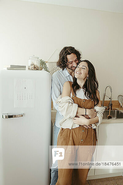 Happy couple with arm around standing in kitchen