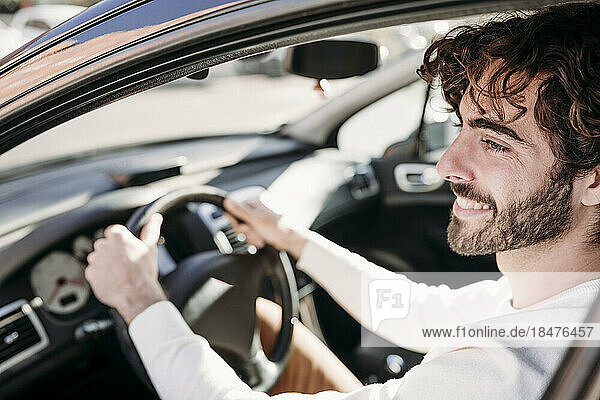 Smiling young man with beard sitting in car