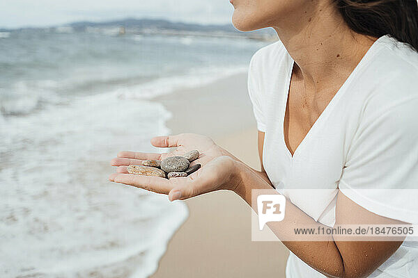 Woman holding pebbles in hand at beach