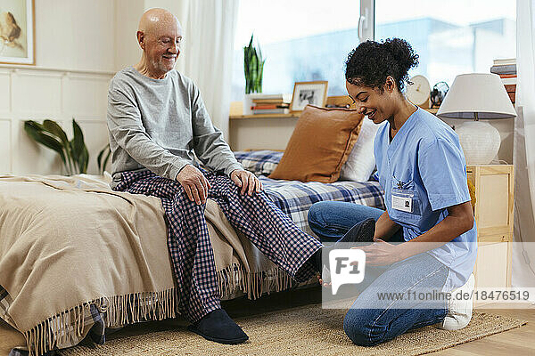 Physical therapist examining senior man's ankle during physical therapy session