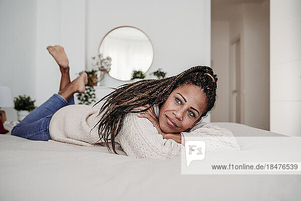 Thoughtful mature woman lying on bed in bedroom