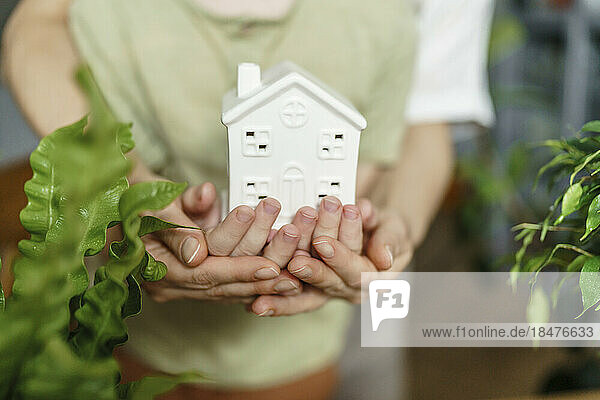 Hands of mother and son holding house model