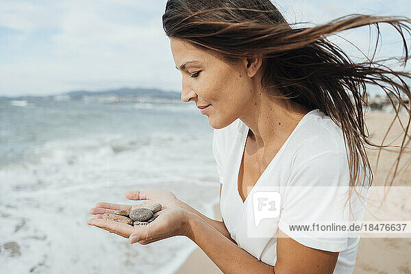 Woman holding pebbles at beach
