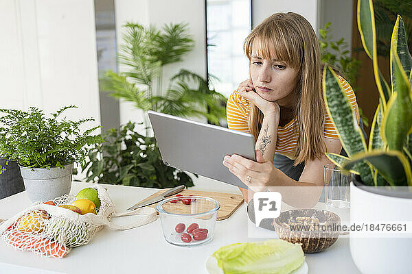 Woman watching tutorial on tablet PC at home