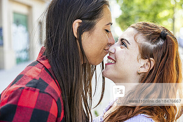Young woman kissing girlfriend's nose