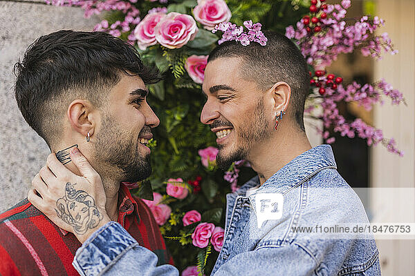 Happy gay couple standing in front of flowering plants