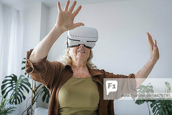 Senior woman with vitiligo skin wearing virtual reality headset at home
