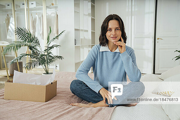 Smiling woman sitting on bed at home