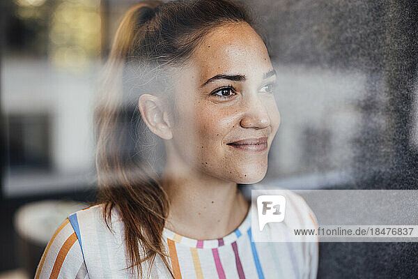 Smiling businesswoman seen through glass