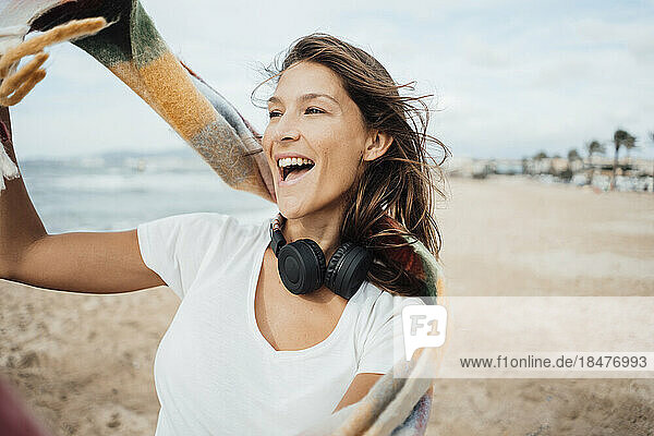 Fröhliche Frau mit Kopfhörern genießt den Strand