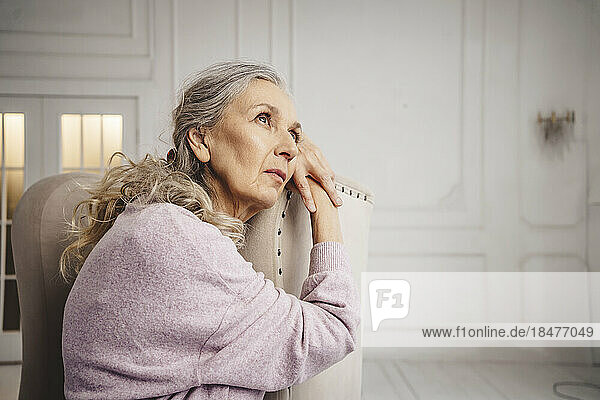 Thoughtful senior woman sitting on chair at home