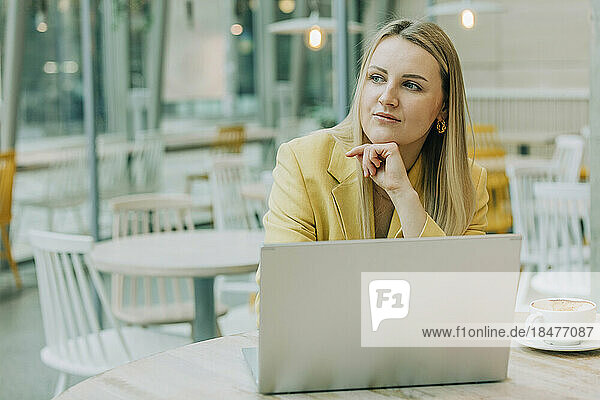 Thoughtful businesswoman with laptop at table in cafe