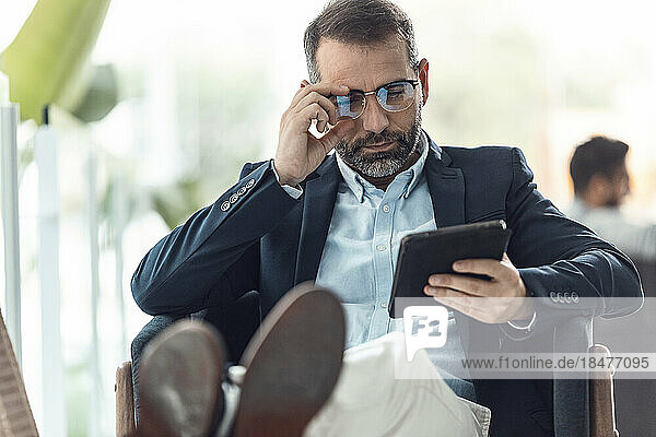 Businessman wearing eyeglasses using tablet PC at workplace
