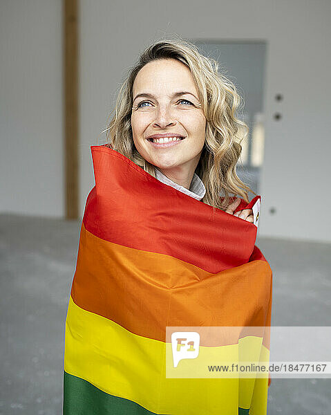 Happy woman wrapped in multi colored flag