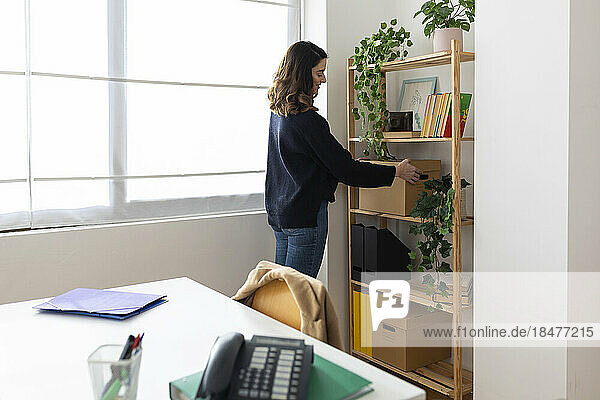 Geschäftsfrau stellt Karton im Büro auf Regal