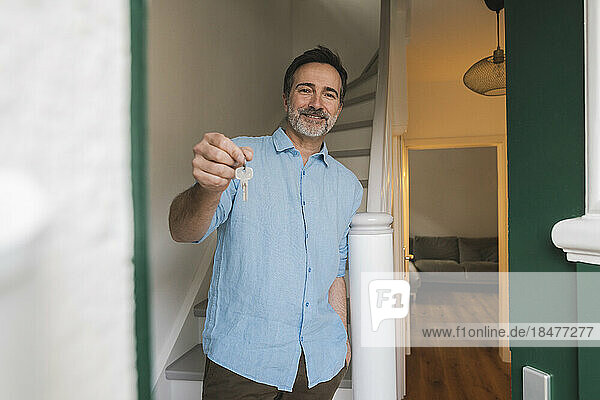 Smiling man showing house key by staircase