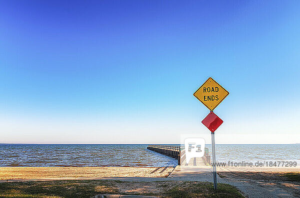 Road sign with Road Ends text in front of pier  Lake Huron  Michigan  USA