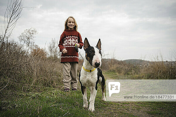 Girl standing with Bull Terrier dog amidst grass