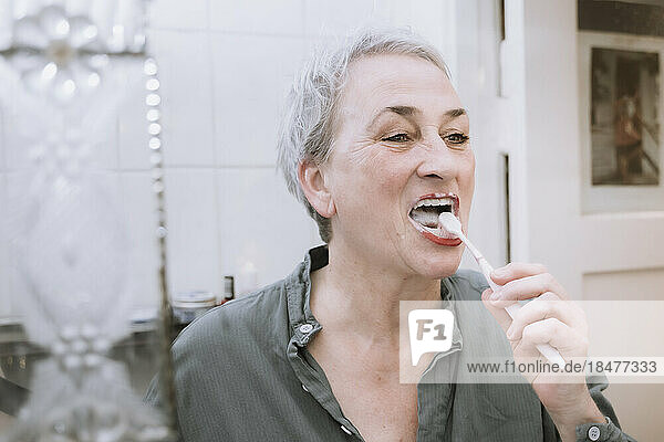 Senior woman brushing teeth in bathroom