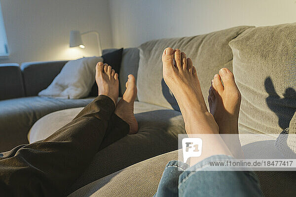 Couple's legs resting on sofa in living room