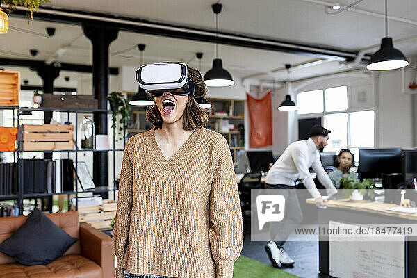 Businesswoman wearing VR glasses standing in office