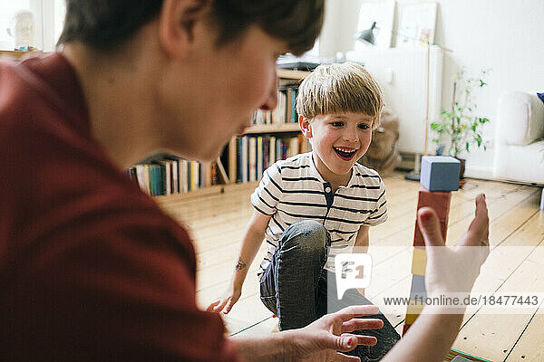 Glücklicher Junge  der zu Hause mit seiner Mutter Bauklötze spielt