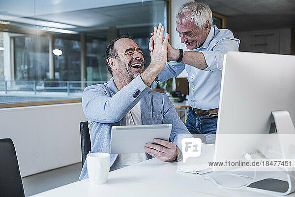 Cheerful business colleagues giving high-five at office