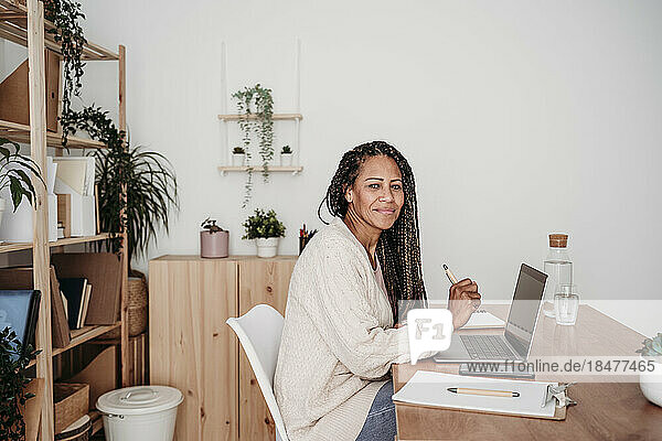 Smiling freelancer with laptop sitting at desk