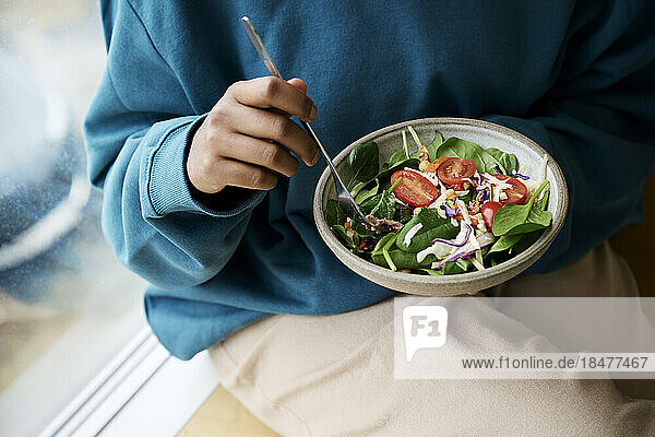Woman holding bowl of fresh healthy salad
