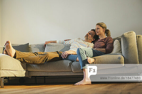 Mature couple spending leisure time resting on sofa at home