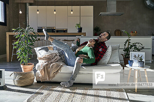 Playful couple enjoying together on couch at home